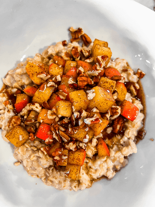 Oatmeal with roasted vegetables and nuts on a white plate
