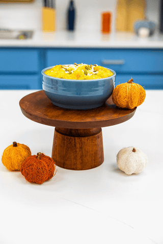 Blue bowl with yellow dessert on a wooden stand in a kitchen setting