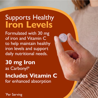 Promotional graphic for a supplement tablet, showing a hand holding a round silver pill against a warm brown and orange background with text about iron levels and vitamin C.
