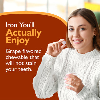 A smiling woman in a white cable-knit sweater holds a small round orange chewable tablet. Large promotional text on the left reads, 'Iron You'll Actually Enjoy.