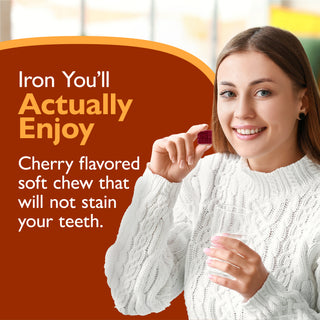 A smiling woman in a white cable-knit sweater holds a small dark red cherry-shaped soft chew. Large orange text on the left reads, 'Iron You’ll Actually Enjoy' and 'Cherry flavored soft chew that will not stain your teeth.