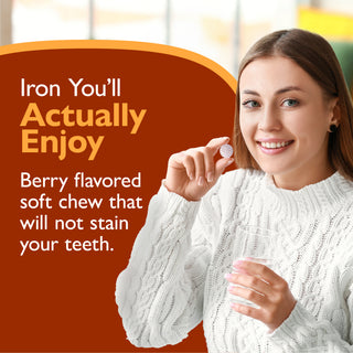 A smiling woman in a white cable-knit sweater holds a small round berry-flavored soft chew. Large promotional text on a dark orange background reads, 'Iron You’ll Actually Enjoy Berry flavored soft chew that will not stain your teeth.