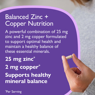 A close-up of a hand holding a supplement capsule against a soft gray background, with a large purple text panel on the left reading 'Balanced Zinc + Copper Nutrition' and detailing 25 mg zinc and 2 mg copper benefits.